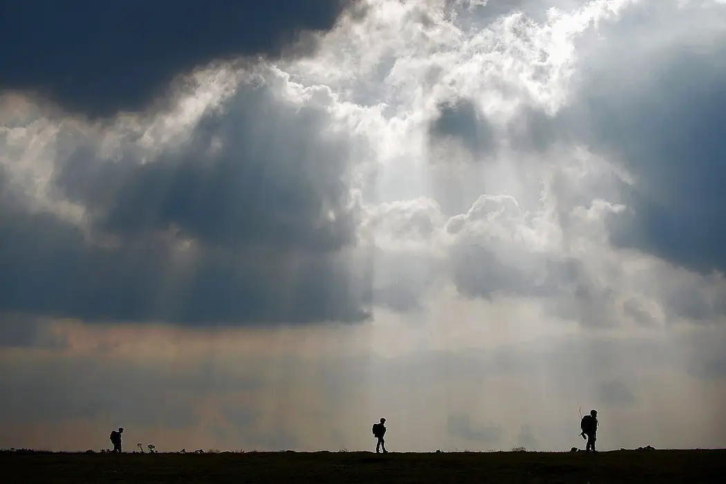 Three Royal Marines trainees silhouetted against a dramatic sky on Bodmin Moor